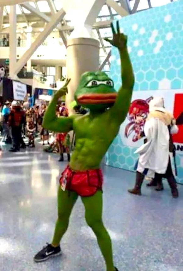 Oslavuje v maske žaby a šortkách na cosplay akcii v interiéri plnom ľudí a stánkov.