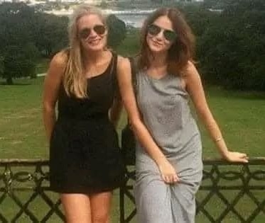 Ospravedlňujem sa, neviem, kto sú tieto osoby. Dve ženy v slnečných okuliaroch pózujú vonku s trávou a stromami v pozadí.