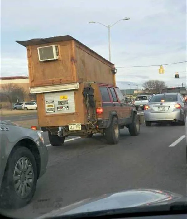 Auto s pripevneným dreveným prístreškom a klimatizáciou na ceste, kreatívne riešenie pre mobilný dom.