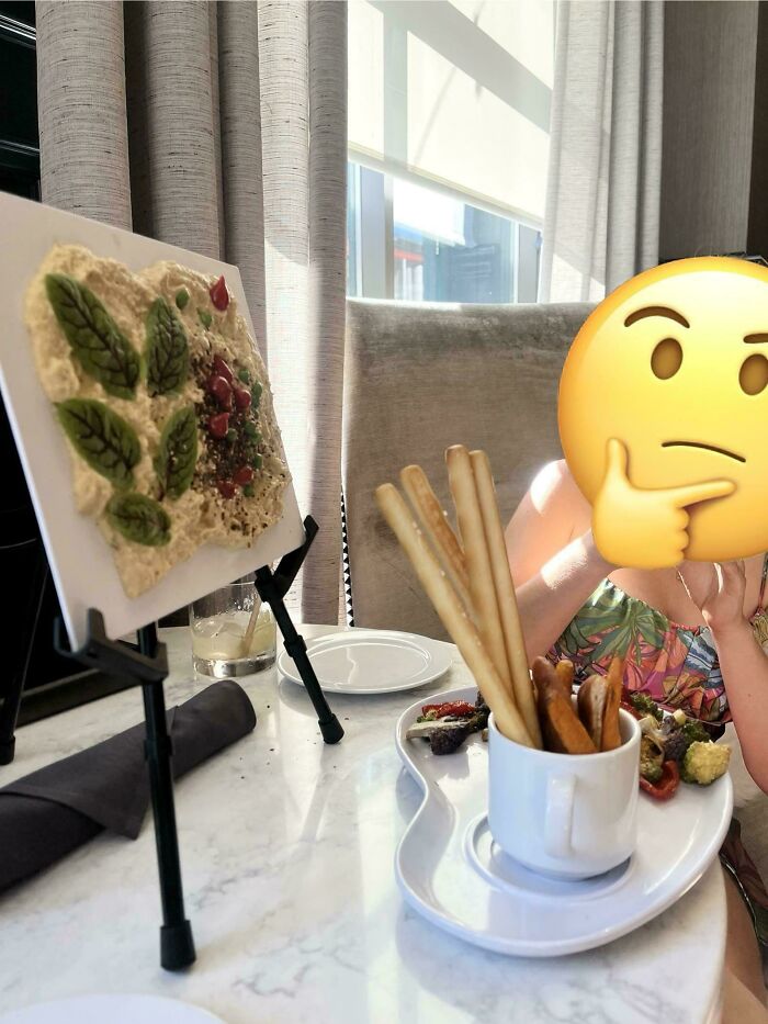 Osoba v kaviarni s tanierom krekrov a dipu, kreatívne prezentovaná jedlá na doske.