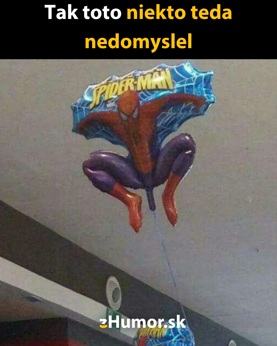 Balón so superhrdinom vo vtipnej póze visí zo stropu v interiéri; humoristický moment.