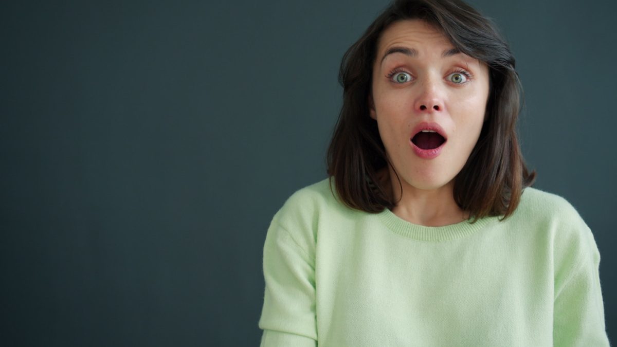 Woman with surprised expression against dark background