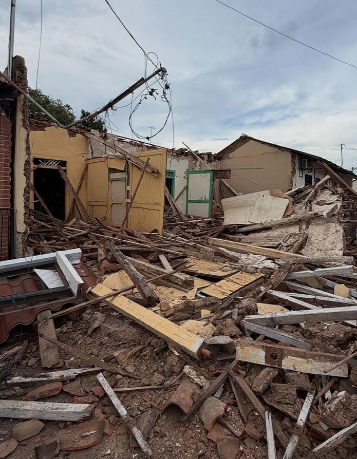 Zrútená budova po silnom zemetrasení, trosky a poškodená infraštruktúra pod šedou oblohou.