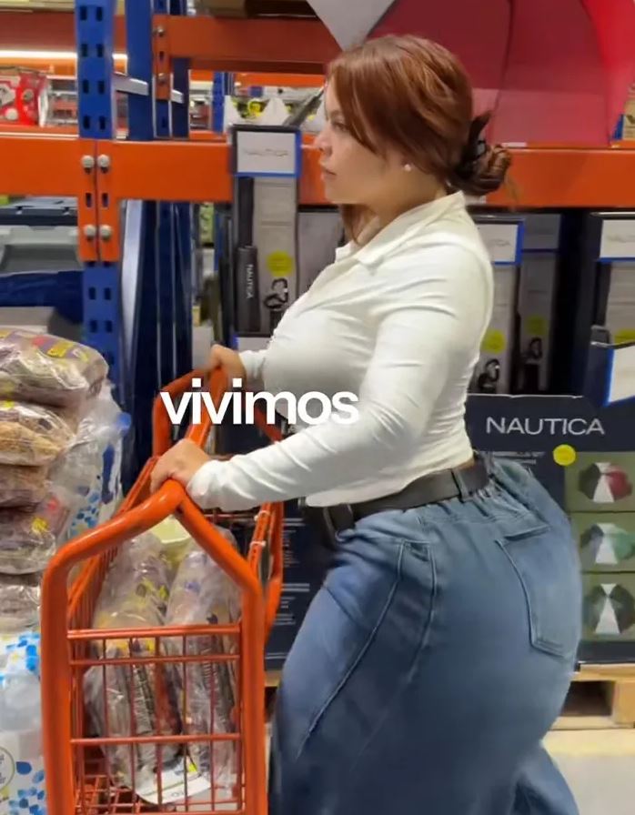 Žena tlačí nákupný vozík v obchode so širokým výberom produktov.