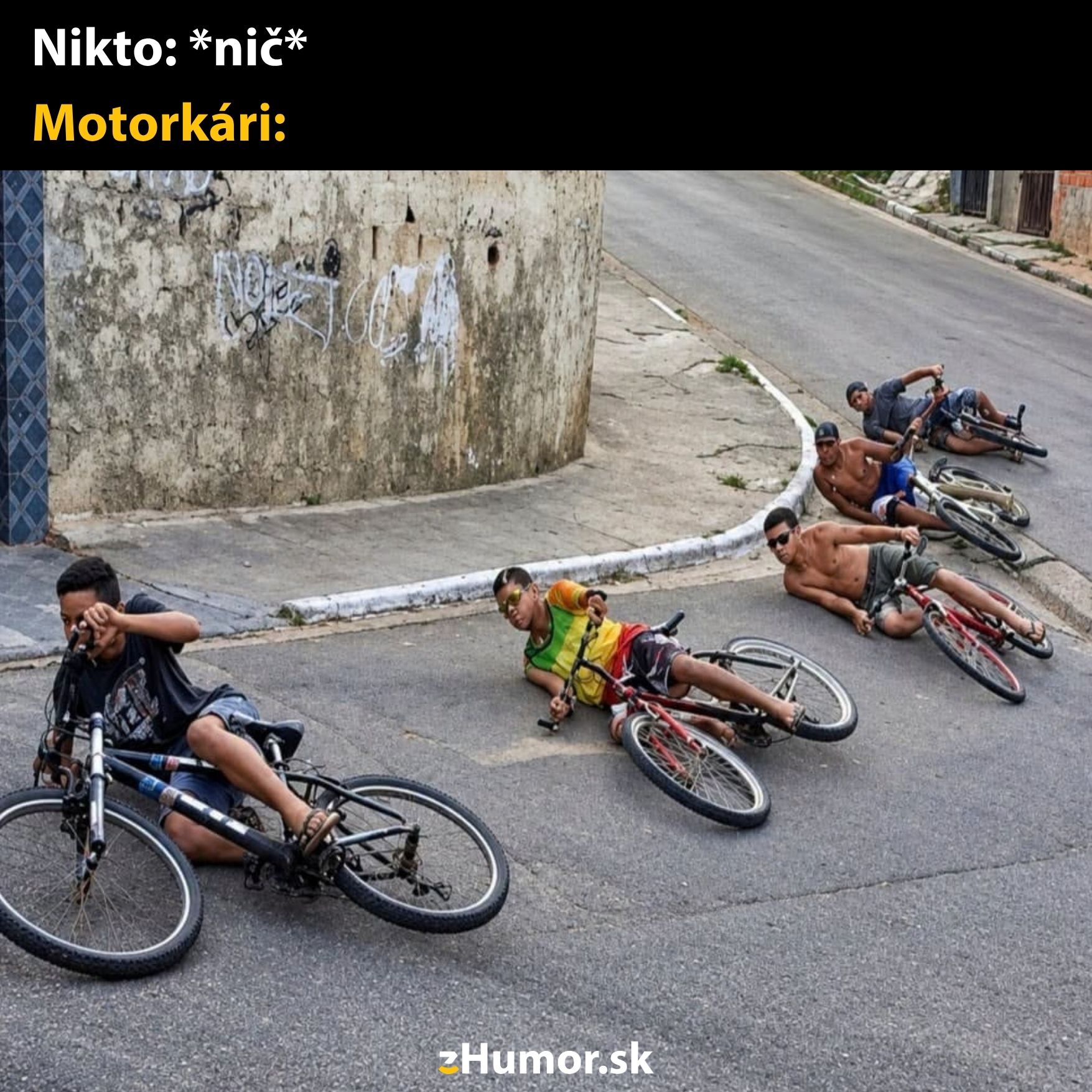 Deti ležia na bicykloch na ceste, imitujú jazdu na motorke v zákrute.