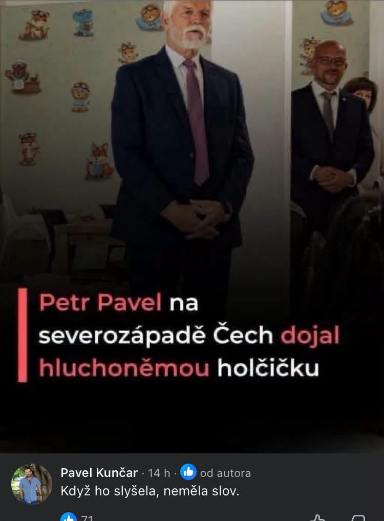 Vysoký muž v obleku počas oficiálnej akcie pred nástennými dekoráciami pre deti.