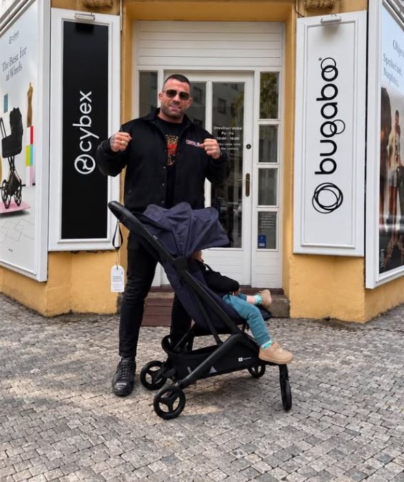 Muž s kočíkom pred obchodom Cybex a Bugaboo na kamennej dlažbe.